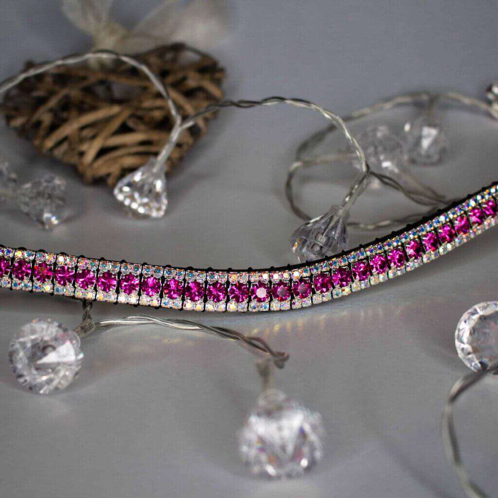 A pink browband sitting on a white back ground with crystal shaped lights