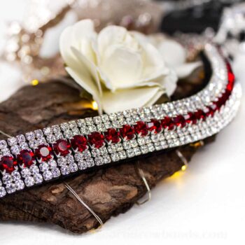 Red Browband with red and clear crystals sitting on tree bark with a cream rose and a white background