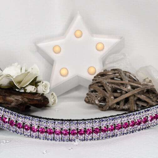 Purple browband with hot pink crystals on a white back ground with a star and wooden ornaments with flowers on the side